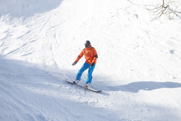 Concepto de invierno, ocio, deporte y personas - Snowboarder activo saltando en las montañas en un día soleado. Primer plano de snowboard. Estación de esquí de Sheregesh