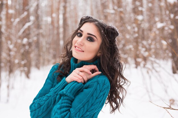 Concepto de invierno, temporada y personas - Close up retrato de mujer joven y bonita caminando en el parque cubierto de nieve