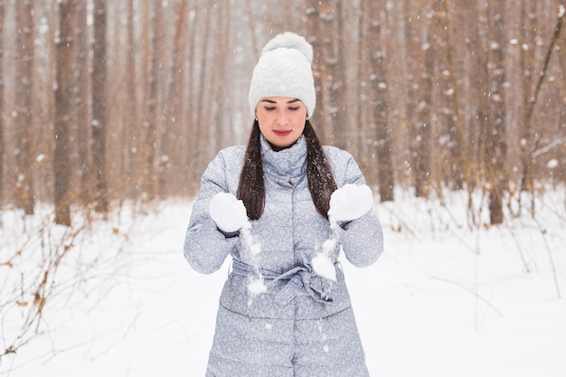 Concepto de invierno, vacaciones y personas - alegre joven está feliz de caminar en el bosque de invierno con