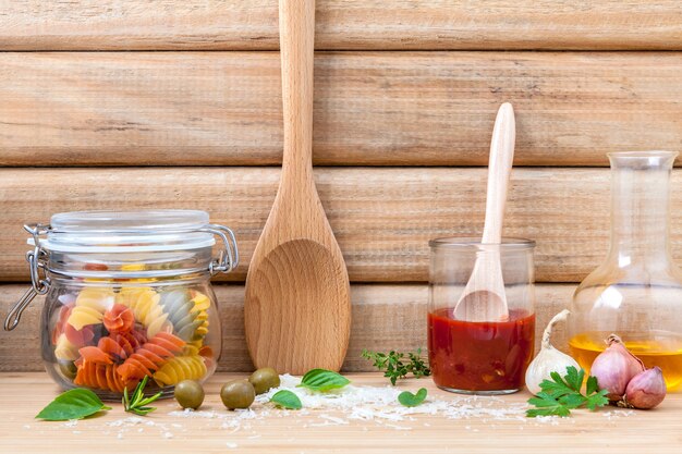 El concepto italiano de la comida secó las pastas con los ingredientes en fondo de madera.