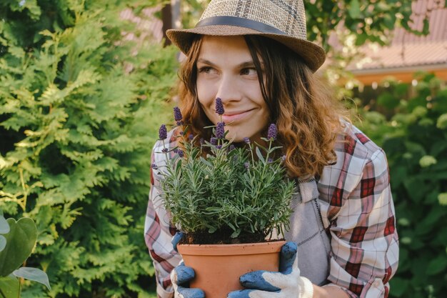 Concepto de jardinería Mujer joven sostiene planta de lavanda en maceta al aire libre