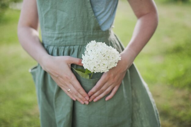 Concepto de jardinería y profesión mujer joven en delantal sosteniendo flores en el jardín en verano