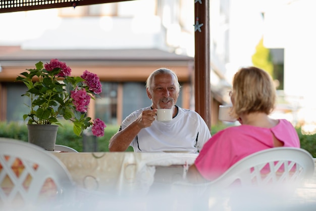 Concepto de jubilación Pareja bebiendo café en el porche Dos hombres y mujeres mayores bebiendo café y sonriendo o discutiendo un plan futuro después de jubilarse