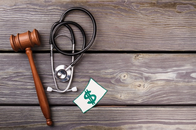 Foto concepto de juicio y salud. mazo de madera y un estetoscopio sobre un escritorio de madera.