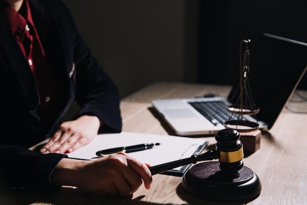 Concepto de justicia y derechoJuez masculino en una sala de audiencias con el mazo trabajando con computadora y anteojos de teclado de acoplamiento en la mesa a la luz de la mañana