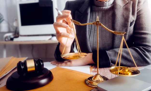 Concepto de justicia y derechoJuez masculino en una sala de audiencias con el mazo trabajando con computadora y anteojos de teclado de acoplamiento en la mesa a la luz de la mañana