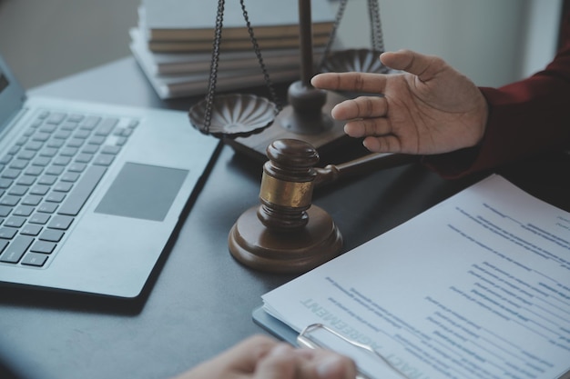 Concepto de justicia y derechoJuez masculino en una sala de audiencias con el mazo trabajando con computadora y anteojos de teclado de acoplamiento en la mesa a la luz de la mañana