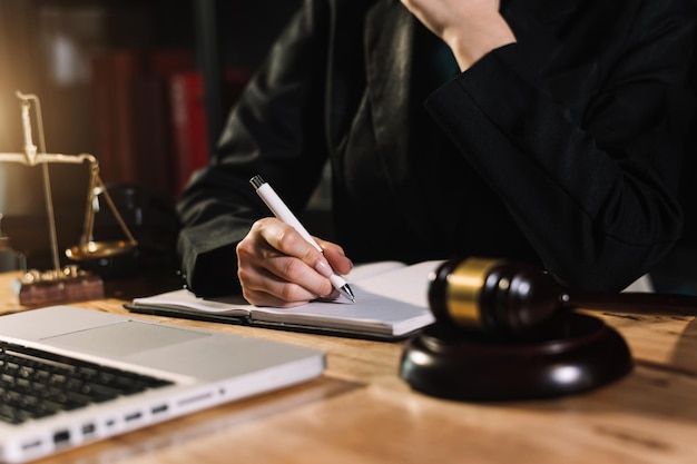 Concepto de justicia y derechoJuez masculino en una sala de audiencias con el mazo trabajando con computadora y anteojos de teclado de acoplamiento en la mesa a la luz de la mañanaxA