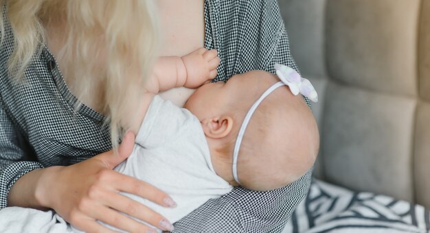 Concepto de lactancia. Joven madre amamantando a su bebé recién nacido en casa, cerrar