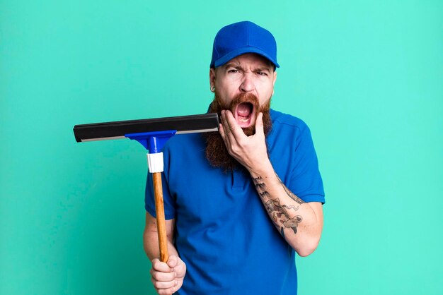 Concepto de lavadora de ventanas de hombre fresco barbudo de pelo rojo adulto joven