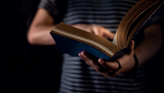 Foto concepto de lectura persona holding open bible book en la mano. tono oscuro, imagen recortada