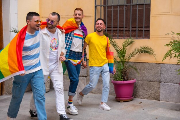 Concepto lgbt amigos hombres gay divirtiéndose en la fiesta del orgullo gay diversidad de jóvenes en el camino de la ciudad a la manifestación con las banderas del arco iris