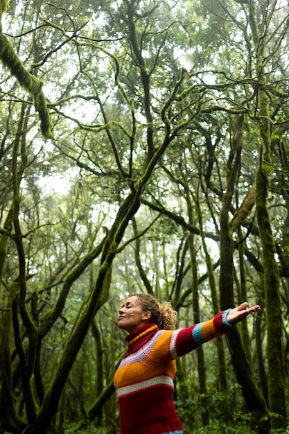 Concepto de libertad y protección del bosque en el día de la tierra Mujer de pie con los ojos cerrados disfruta sintiéndose con el bosque y los árboles alrededor Ejercicio de atención plena mujer adulta Momento positivo con la naturaleza