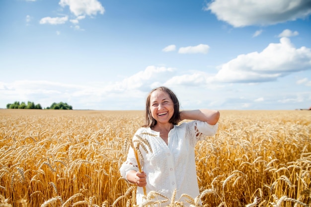 Concepto de libertad y serenidad con una modelo femenina natural madura Modelo femenina caucásica de unos 60 años caminando por un campo de trigoxDxA