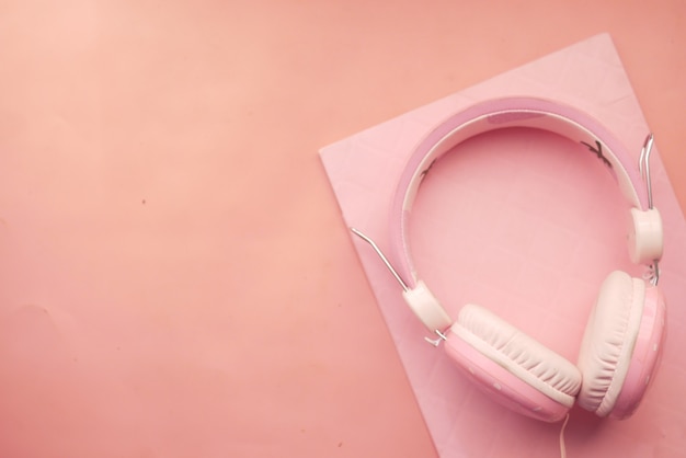 Concepto de libro de audio auriculares y bloc de notas sobre fondo rosa