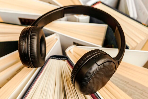 Foto concepto de libro de audio con gran montón de libros y auriculares. estudio en línea, aprendizaje o autoaprendizaje.