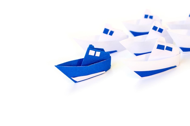 Concepto de liderazgo con barco de papel azul aislado sobre fondo blanco. Conceptos de liderazgo y manejo.