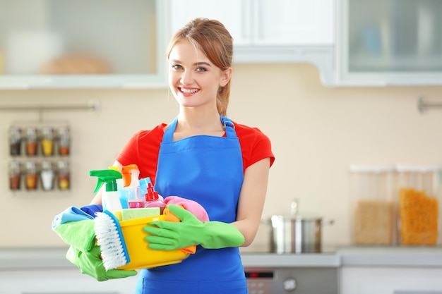 Concepto de limpieza Mujer joven sostiene lavabo con líquidos de lavado y trapos en las manos