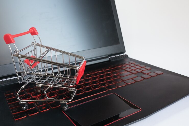 Foto concepto en línea de compras - carro de compras en el teclado negro. carro de metal rojo en un teclado portátil