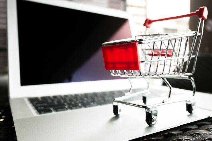 Foto concepto en línea de compras - carro rojo de la carretilla en la computadora portátil