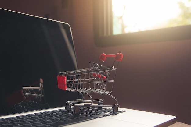 Concepto en línea que hace compras - carro o carretilla de compras en un teclado de la computadora portátil. servicio de compras en la web online.