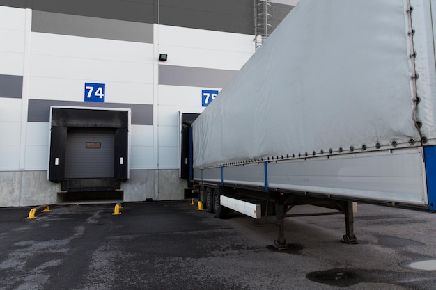 concepto de logística, almacenamiento, envío, transporte y carga: puertas de almacén y carga de camiones