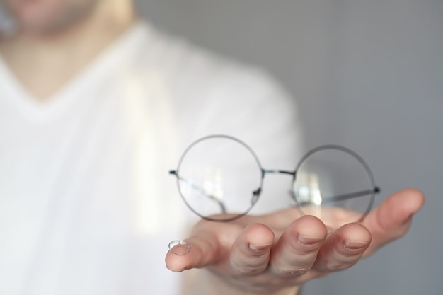 Foto el concepto de mala visión. sostenga una lente de contacto y anteojos en la mano. un cartel para publicidad de gafas y lentes.