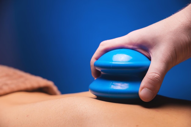 Foto el concepto de una mano de cuerpo saludable poniendo un frasco de goma azul para el masaje en la espalda de un hombre en primer plano