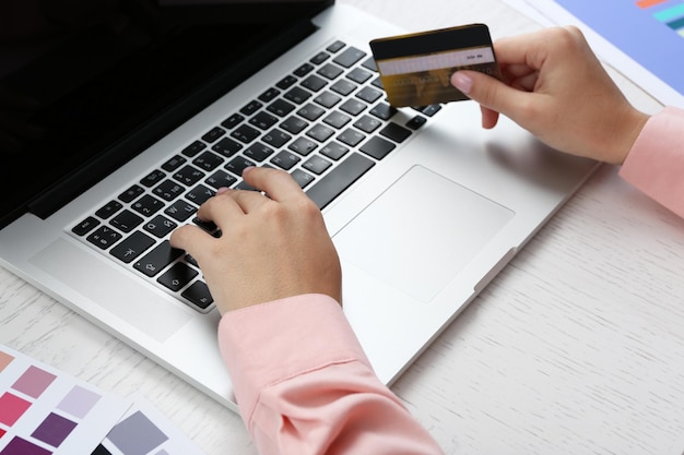 Concepto para las manos de compras por Internet con portátil y tarjeta de crédito