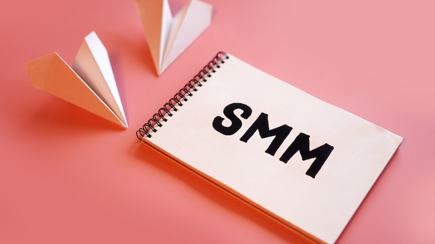 Concepto de marketing en redes sociales - plan SMM en un cuaderno sobre un fondo rosa