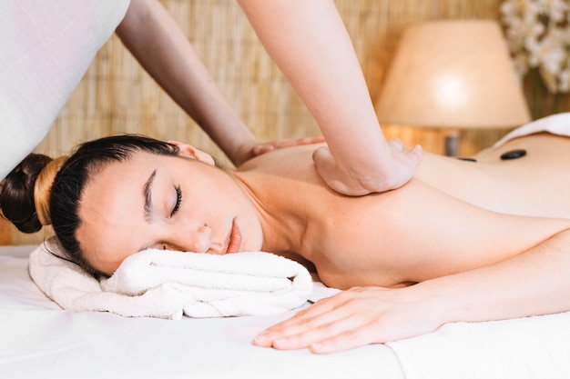 Foto concepto de masaje con piedras en espalda de mujer