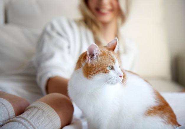 concepto de mascotas, animales y personas - mujer joven feliz con gato en la cama en casa