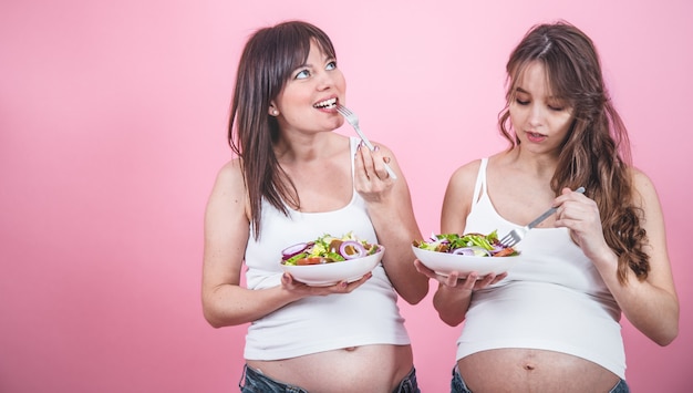 Concepto de maternidad, dos mujeres embarazadas comiendo ensalada fresca