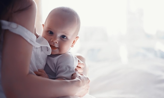 Concepto de maternidad. Una joven madre alimenta a su pequeño bebé. Primer señuelo y lactancia. Familia numerosa vestida de blanco.