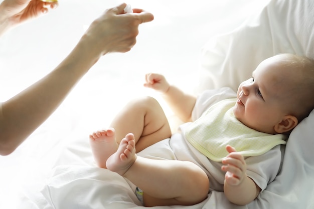 Concepto de maternidad. Una joven madre alimenta a su pequeño bebé. Primer señuelo y lactancia. Familia numerosa vestida de blanco.