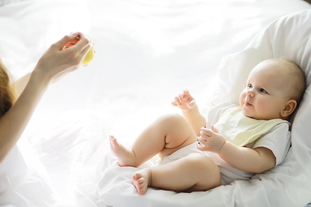 Concepto de maternidad. Una joven madre alimenta a su pequeño bebé. Primer señuelo y lactancia. Familia numerosa vestida de blanco.