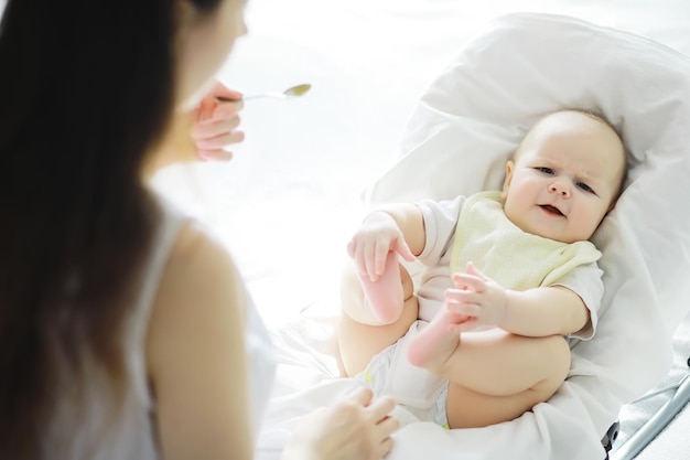 Concepto de maternidad. Una joven madre alimenta a su pequeño bebé. Primer señuelo y lactancia. Familia numerosa vestida de blanco.