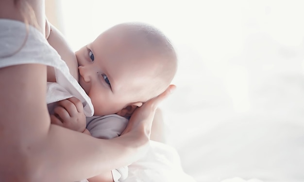 Concepto de maternidad. Una joven madre alimenta a su pequeño bebé. Primer señuelo y lactancia. Familia numerosa vestida de blanco.