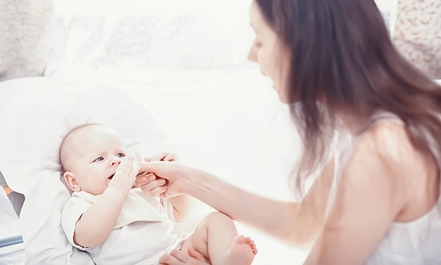 Concepto de maternidad. Una joven madre alimenta a su pequeño bebé. Primer señuelo y lactancia. Familia numerosa vestida de blanco.