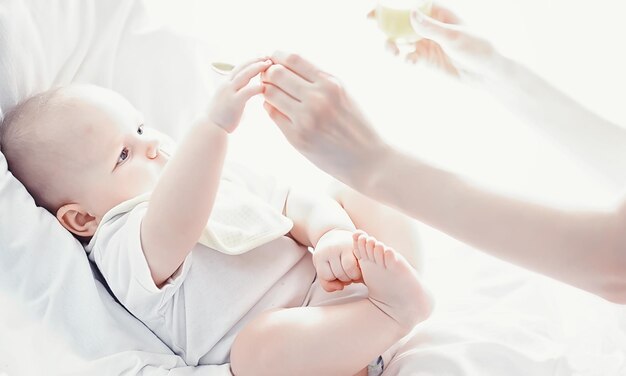 Concepto de maternidad Una joven madre alimenta a su pequeño bebé Primer señuelo y lactancia Familia numerosa vestida de blanco