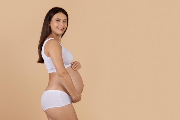 Foto concepto de maternidad retrato de hermosa mujer joven embarazada en ropa interior