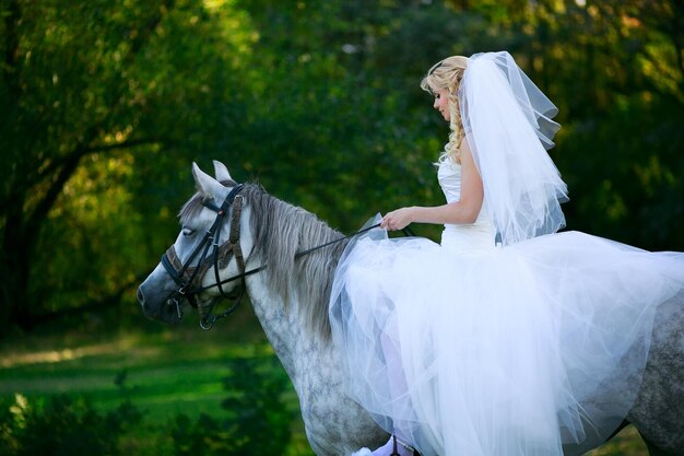 Concepto de matrimonio y emoción. Novia a caballo en el bosque