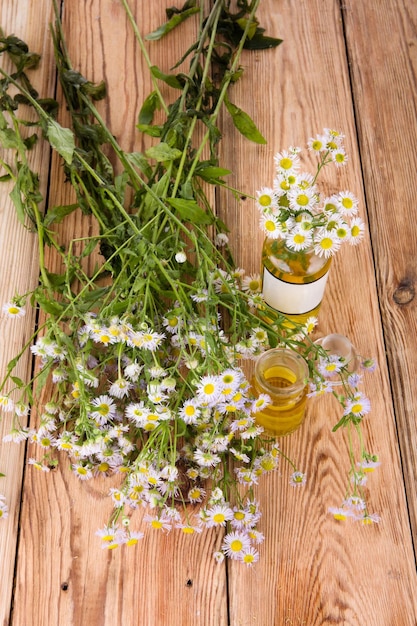 Concepto de medicina alternativa aceite fragante en una botella con flores de manzanilla en la mesa de madera