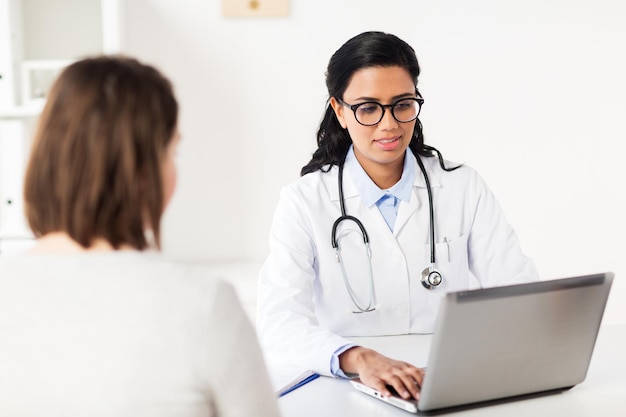 Concepto de medicina, atención médica, tecnología y personas: médico con computadora portátil y paciente en el hospital