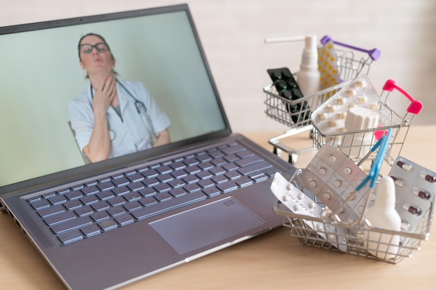 Concepto de medicina y farmacia en línea Una doctora realiza una consulta en línea y recomienda medicamentos Mini carro con tabletas en la computadora portátil