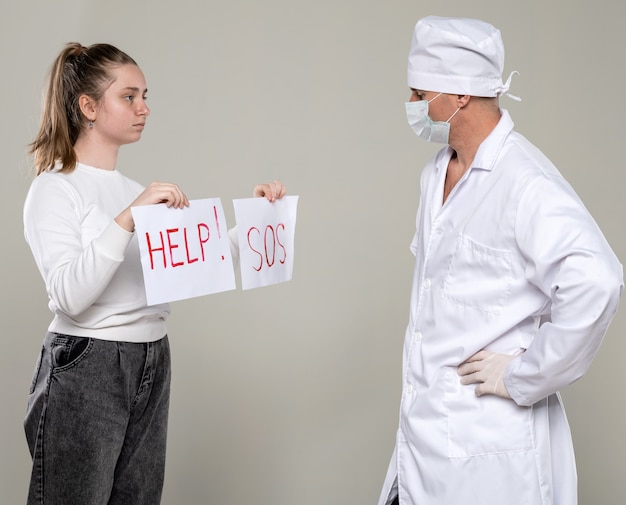 Concepto médico y sanitario. Jovencita pidiendo ayuda a un médico sobre pared gris