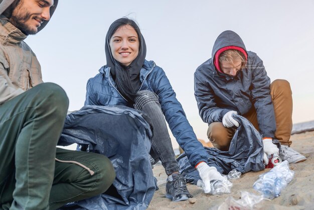 Concepto de medio ambiente Jóvenes recogiendo basura en la playa bastante joven sonriendo