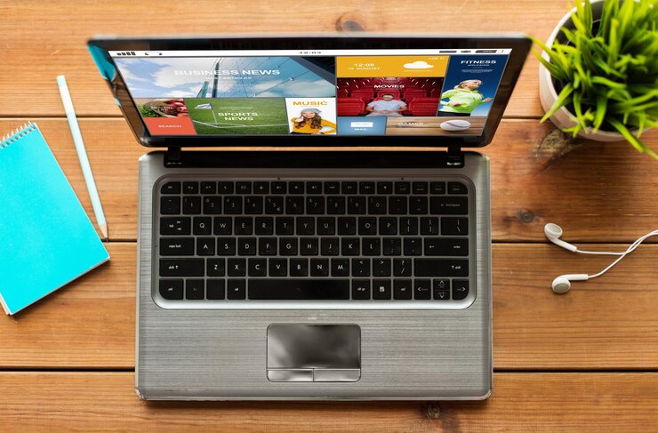 Foto concepto de medios de comunicación, educación, negocios y tecnología: cierre de una computadora portátil con una aplicación de noticias en internet en la pantalla sobre una mesa de madera