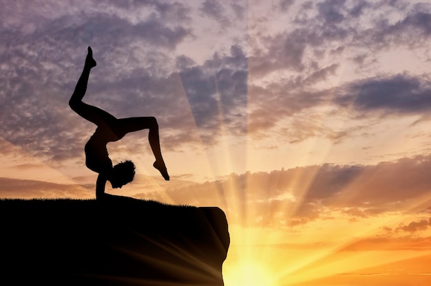 Concepto de meditación y relajación. Silueta de una niña practicando ejercicios de yoga en el fondo del atardecer