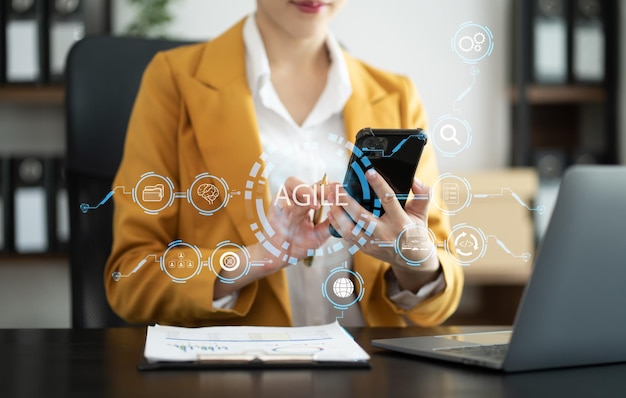 Concepto de metodología de desarrollo ágil Mano de negocios usando computadora portátil y tableta con icono ágil de pantalla virtual en el concepto de tecnología digital de oficina moderna